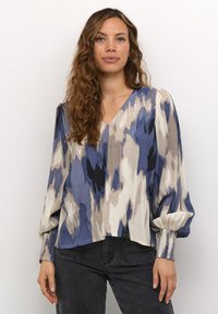 Bluza s V-izrezom u kombinaciji plavih, krem i sivih uzoraka; napufane rukave s teksturiranim manžetama; opušteni kroj, lagani materijal.