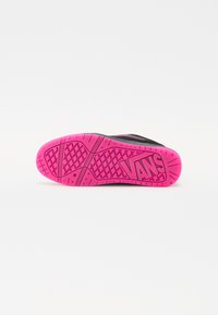 Čierne tenisky s textúrovanou podrážkou, ktorá má jasne ružovú gumovú podrážku a logo "VANS". Dizajn s protišmykovou funkciou a vzorovaným profilom.