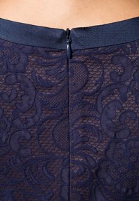 Námořnická květinová krajková sukně má texturovaný design, zapínání na zip vzadu a hladký pas pro přiléhavý vzhled.