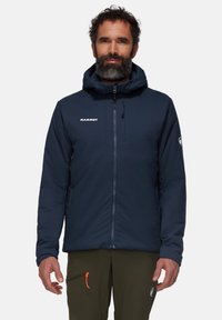Marinblå isolerad jacka med huva, dragkedjestängning fram och logodetalj. Har fickor med dragkedja och kontrasterande oranga accenter.