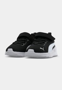 Chaussures de sport noir et blanc avec un dessus en mesh, une sangle Velcro, une semelle texturée et le logo Puma sur le côté. Conçues pour le confort et le soutien.