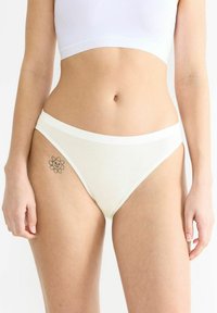 Weiße Baumwollbikini-Unterwäsche mit einem kontrastierenden Bund. Besitzt eine glatte Textur und ein florales Tattoo am Oberschenkel.