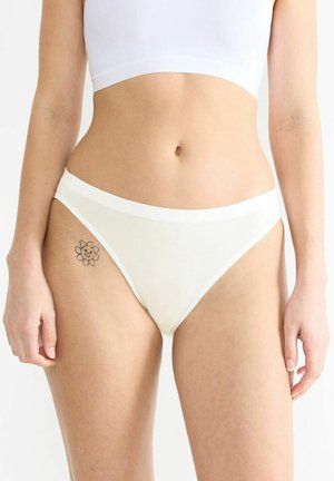 Weiße Baumwollbikini-Unterwäsche mit einem kontrastierenden Bund. Besitzt eine glatte Textur und ein florales Tattoo am Oberschenkel.