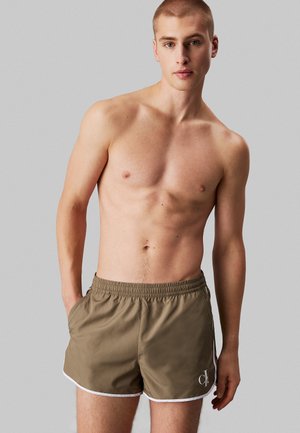 Bañador de hombre, color caqui, con cintura elástica, ribete blanco, bolsillos laterales, logo en el muslo izquierdo, fabricado con tejido ligero.