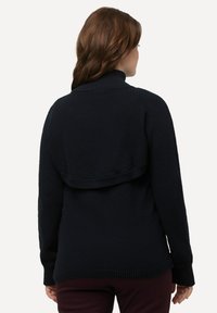 Marineblauer Strickpullover mit hohem Kragen, strukturiertem Stoff und einem kürzeren Rückendesign. Die Bündchen sind gerippt für zusätzliche Stabilität.