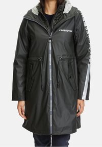 Tmavě zelená nepromokavá parka s kapucí, zapínáním na zip, šňůrkou v pase, postranními kapsami a reflexními prvky. Značení "CROSSOVER".