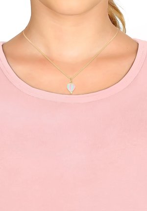 Goldkette mit einem Heißluftballon-Anhänger in Pastellfarben (Blau, Rosa, Grün) auf einer feinen Kette, getragen auf einem rosa Oberteil.