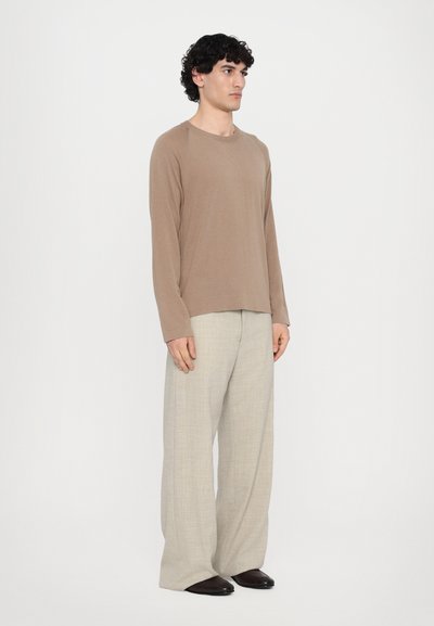 Brown long-sleeve shirt paired with light beige wide-leg trousers, featuring a soft texture and relaxed fit. Worn with dark shoes.