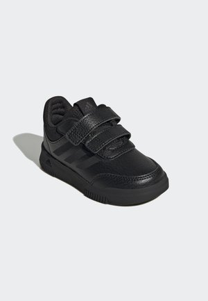 Baskets de sport noires avec une tige en cuir lisse, des accents en mesh, deux sangles velcro et une semelle en caoutchouc texturée. Présente trois bandes noires.