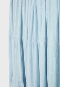 Tissu bleu clair avec de subtiles lignes scintillantes verticales et des détails de couture rassemblés créant de doux plis.