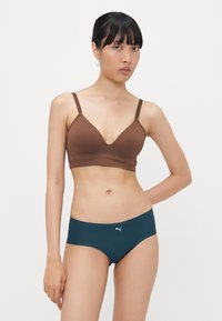 Bralette castanho sem costuras com decote em V e alças ajustáveis, combinado com cuecas hipster em verde-água com um logótipo branco. Textura suave, design minimalista.