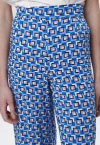 Blauwe gemusterde broek heeft een geometrisch ontwerp met vierkanten in blauw, crème en bruin, gemaakt van een zachte stof.
