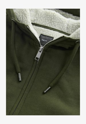 Olive green zip-up hoodie with a soft cream sherpa lining, metal zipper, and drawstrings. Features a label reading "NEXT" inside.