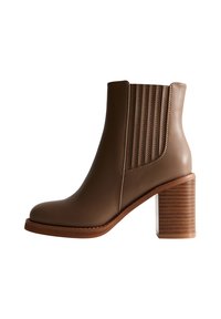 Brązowy skórzany botek za kostkę z piętą w kształcie słupka i bocznymi panelami z elastycznego materiału, ułatwiającymi zakładanie, prezentowany w widoku bocznym na białym tle.