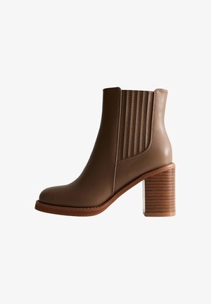 Botín de cuero marrón hasta el tobillo con tacón de bloque apilado y paneles laterales elásticos para facilitar su uso, mostrado en vista lateral sobre un fondo blanco.