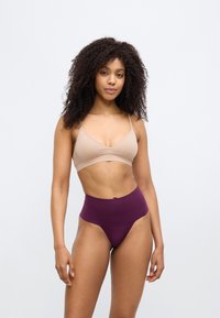 Γυμνό ασύρματο σουτιέν με λεπτές τιράντες συνδυασμένο με σλιπ μπικίνι ψηλόμεσο σε μπορντό, και τα δύο από απαλό, ελαστικό ύφασμα.
