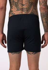 Boxer shorts de algodón negro con una cinturilla elástica, con una textura suave y sin patrones ni elementos visibles.