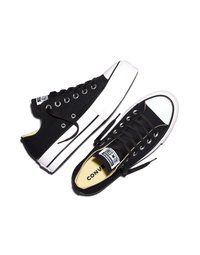 Par črnih nizkih superg Converse All Star z belimi gumijastimi podplati in kapicami na prstih, črnimi vezalkami ter logotipom na jezičku in petnem traku.