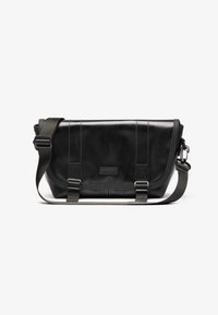 Borsa a tracolla nera realizzata in materiale resistente, con chiusura a pattina, tracolla regolabile e dettagli del logo frontale.