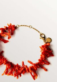 Collar de coral rojo con piezas de forma irregular, cadena de oro y cierre de langosta. Presenta un pequeño acento redondo cerca del cierre.