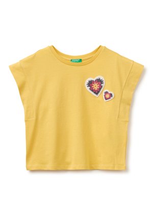 Gelbes kurzärmeliges Cropped-Top mit zwei bestickten herzförmigen Blumenpatches auf der linken Brust.