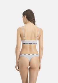 Ensemble bralette et string en coton gris avec des bretelles fines. Présente un logo de marque noir contrastant le long de la bande. Texture lisse, design minimal.