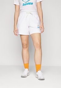 Hvite idrettsshorts med elastisk midje og snor, med en flerfarget Lotto-logo. Kombinert med oransje stripete sokker og hvite sko.
