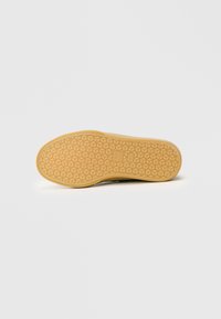 Talpa de pantof cu un model în fagure, având o bază din cauciuc bej și urme ușoare de zgâriere, indicând uzură și o aderență texturată.