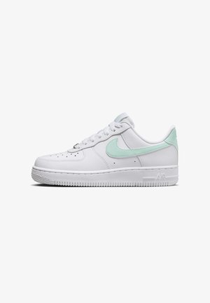 Baskets en cuir blanc avec le logo Nike Swoosh vert clair et languette de talon, embout perforé, et semelle en caoutchouc blanche.