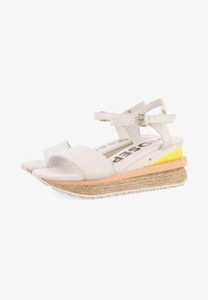 Bílé wedge sandály s texturovanou espadrilovou podrážkou, otevřeným špičkovým designem, nastavitelným páskem kolem kotníku a vrstvenými barevnými akcenty v broskvové a žluté barvě.