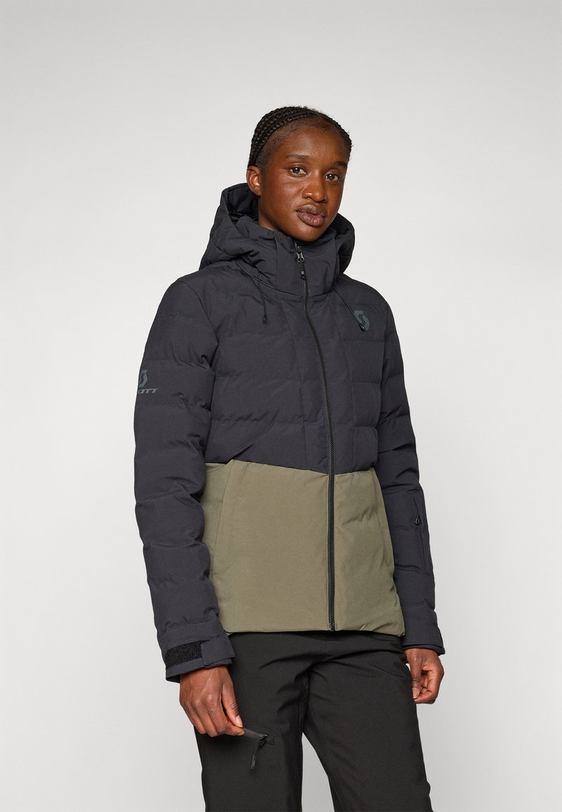 Schwarze und olivgrüne Steppjacke mit hohem Kragen, Frontreißverschluss und elastischen Bündchen. Mit einem Logo auf der linken Schulter und der Brust.