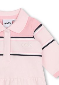Robe polo rose à manches courtes, col et logo BOSS. Présente des rayures horizontales en marine, blanc et rose. Tissu texturé.