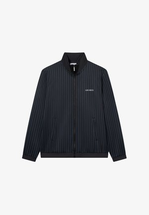 Granatowa kurtka zapinana na zamek z wysokim kołnierzem, z cienkimi pionowymi paskami i dwiema kieszeniami z przodu. Logo "LES DEUX" na lewej piersi.