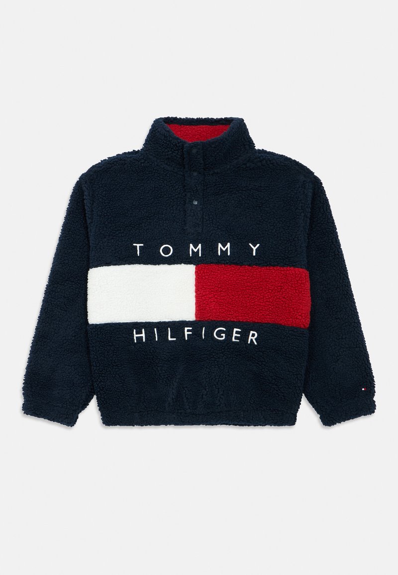 Pile blu navy con collo alto. Presenta un pannello a strisce bianche e rosse con il logo "TOMMY HILFIGER" in bianco sul petto.