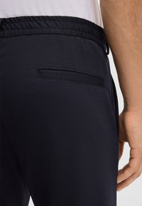 Pantaloni navy realizzati in tessuto strutturato con vita elastica, dotati di una tasca posteriore elegante e una vestibilità rilassata.