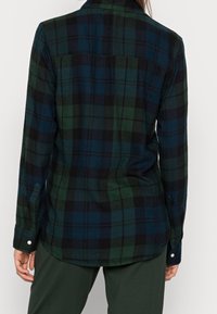 Grünes und marineblaues karriertes Flanellhemd, langärmelig, mit abgerundetem Saum, Knopf-Manschetten, ausgestattet mit einer Rückenpasse und zwei hinteren Abnähern für Struktur.