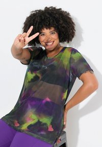 Gennemsigtig sort t-shirt med et tie-dye mønster i violet, grøn og antydninger af pink. Korte ærmer og rund halsudskæring, med sideslidser.