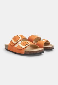 Sandali in suede arancione con due larghe cinghie, caratterizzati da dettagli in oro sulle fibbie, un plantare in sughero naturale e una suola in gomma nera testurizzata.