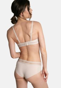 Ensemble soutien-gorge et culotte beige, avec des bretelles réglables et une texture douce et lisse. La culotte est dotée d'une ceinture élastique rayée contrastante.