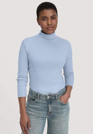 Lichtblauwe coltrui van zacht breimateriaal, met lange mouwen en een getailleerd ontwerp, gecombineerd met high-waisted vervaagde denim jeans.