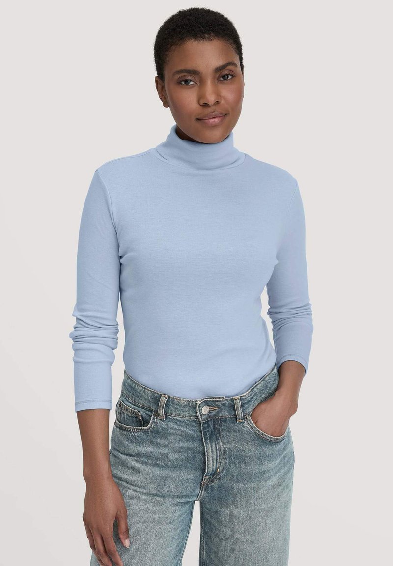 Lichtblauwe coltrui van zacht breimateriaal, met lange mouwen en een getailleerd ontwerp, gecombineerd met high-waisted vervaagde denim jeans.