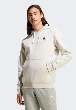 Felpa con cappuccio beige chiaro, dotata di tasca frontale e con un logo nero sul petto. Tessuto morbido con una vestibilità comoda.
