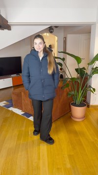 Tamsiai mėlyna pūkinė striukė su aukštu apykakle, priekyje su spaudėmis ir dviem šoninėmis kišenėmis. Dėvima kartu su juodomis kelnėmis ir derinama su juodais batais.