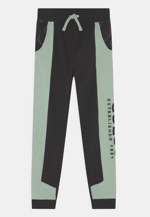 Czarne i miętowo-zielone spodnie dresowe z regulowanym ściągaczem w pasie, bocznymi kieszeniami oraz nadrukiem "ESTABLISHED 1981" na nogawce.