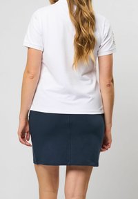 Vit polo-shirt med krage och korta ärmar, matchad med en mörk marinblå knälång kjol, slät textur, enkelt mönster.