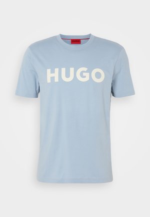 Světle modré bavlněné tričko s krátkými rukávy a kulatým výstřihem. Na přední straně se nachází výrazný bílý nápis "HUGO", bez dalších vzorů nebo akcentů.