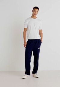 Hvit bomulls t-skjorte kombinert med marineblå joggebukser med snor i livet og logo-detaljer, fullført med hvite sneakers.