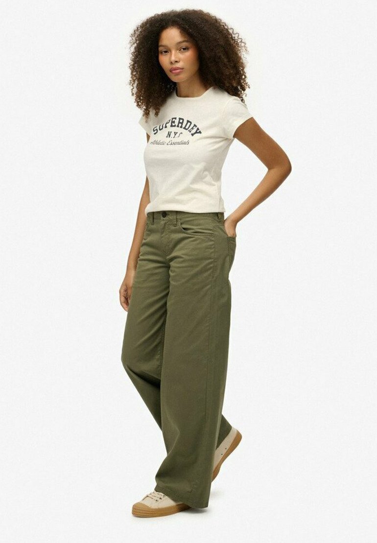 Witte t-shirt met 'Superdry NYC' print, gecombineerd met olijfgroene wijde broek en beige sneakers. Eenvoudige, casual outfit met een ontspannen pasvorm.