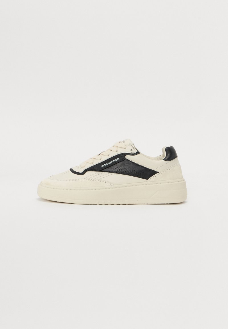 Basket en cuir crème avec un panneau noir texturé, bout rond, semelle plate et couture ton sur ton ; dispose d'une fermeture à lacets et de détails de marque.