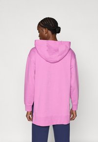 Roosa kapuutsiga dressipluus lõdva istuvusega, pikkade varrukatega ja soonikuhemmega. Sile tekstuur ja kapuutsi reguleeritav nöör.